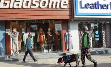An armed forces personnel equipped with Sniffer dog walk along side a street in Lalchowk. Authorities in Srinagar intensified frisking and forces deployment ahead of G20 Summit in Kashmir. [FPK Photo / Umar Farooq]