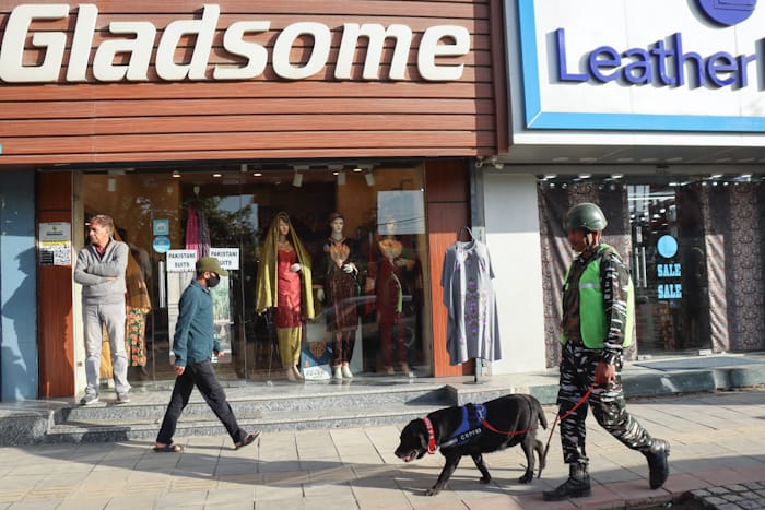 An armed forces personnel equipped with Sniffer dog walk along side a street in Lalchowk. Authorities in Srinagar intensified frisking and forces deployment ahead of G20 Summit in Kashmir. [FPK Photo / Umar Farooq]